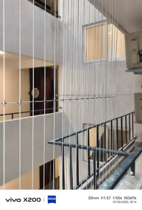 Vertical invisible grill cables protecting apartment balcony with courtyard view